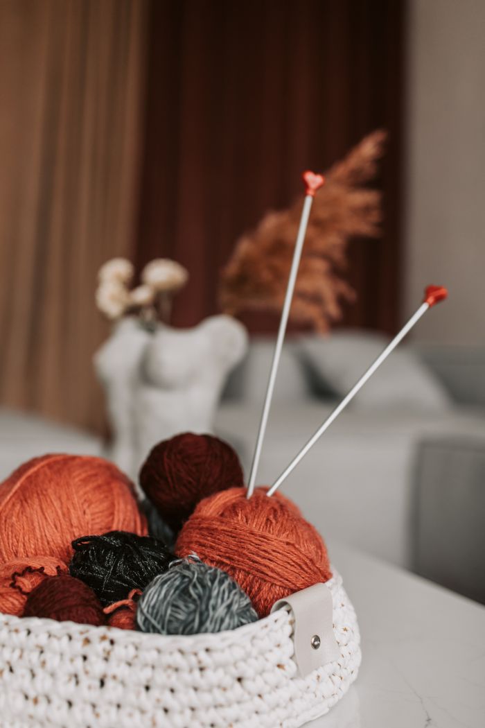 A cozy indoor setting with a basket of colorful yarns and knitting needles, perfect for crafting enthusiasts.