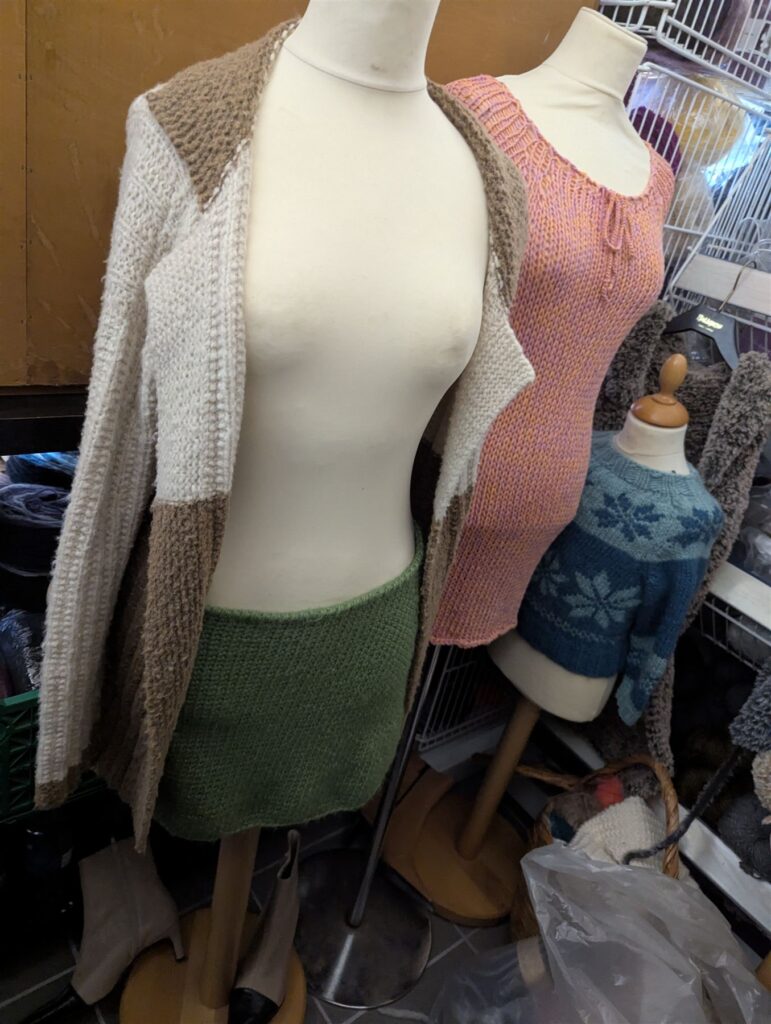 Lang cardigan i hvid og brun på en udstillingsdukke